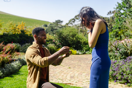 Man proposing to surprised woman in garden, capturing joyful engagement moment. romance, couple,...