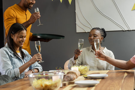 Friends toasting with champagne at dinner party, celebrating together joyfully. Celebration, festive, friendship, gathering, togethernessの写真素材