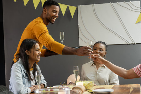 Friends celebrating at home, toasting with champagne and enjoying festive gathering. Celebration,...