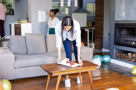 Woman arranging snacks on coffee table at home during festive celebration. party, delicious, gathering, holiday, decoration, preparationの写真素材