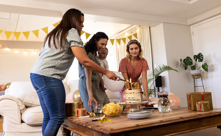 Family celebrating birthday at home, cutting cake with joyful smiles and decorations. Celebration, happiness, party, togethernessの写真素材