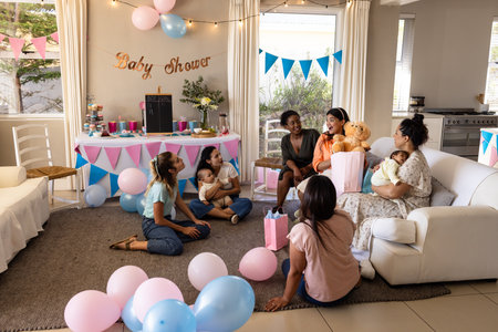 Women celebrating baby shower with gifts and balloons in cozy living room. Celebration, family, present, event, festive, happinessの写真素材