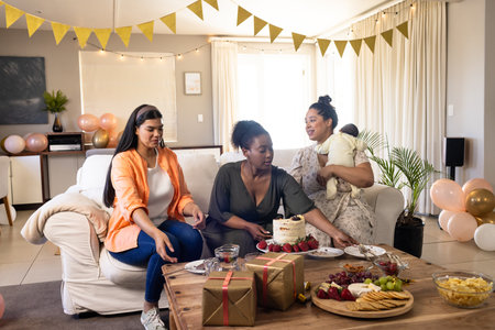Women celebrating at home, enjoying cake and snacks with festive decorations. Celebration, party, friendship, happiness, eventの写真素材
