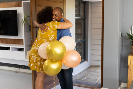 Friends hugging warmly while celebrating at home with colorful balloons. Celebration, togetherness, friendship, joy, gathering, funの写真素材
