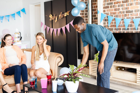 Man serving drinks at baby shower, guests smiling and enjoying celebration. party, gathering, happiness, socializing, beverages, familyの写真素材