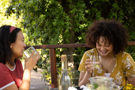 At outdoor gathering, friends laughing and drinking together, having fun. celebration, outdoors, drinks, party, happiness, lifestyleの写真素材