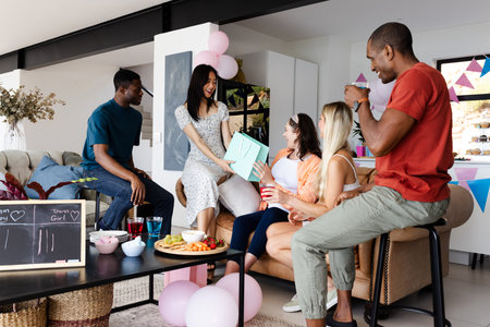 Friends celebrating at home, exchanging gifts and enjoying drinks with laughter. Celebration, party, friendship, gifting, holiday, funの写真素材