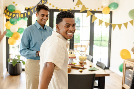 Friends celebrating birthday at home, smiling and enjoying festive decorations. Celebration, party, happiness, friendship, balloons, cakeの写真素材