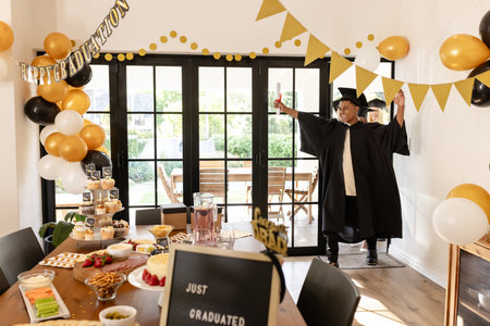 Graduate celebrating with friends at home, holding diploma and smiling joyfully. Graduation, celebration, friendship, achievement, success, partyの写真素材