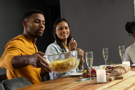 Friends enjoying dinner together, sharing food and drinks at festive table. Celebration, friendship, dining, togetherness, party, cuisineの写真素材