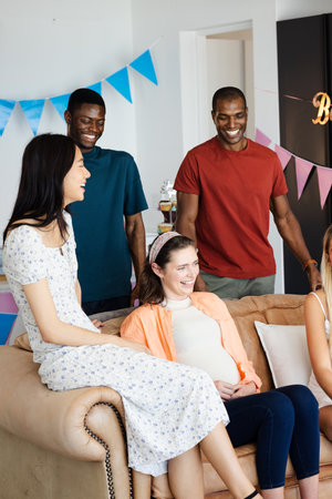 Friends celebrating together at home, smiling and enjoying joyful moments on couch. Celebration, friendship, happiness, gathering, togetherness, living roomの写真素材