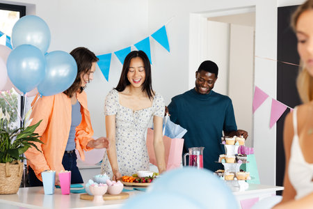 Friends celebrating at home, enjoying snacks and drinks with colorful decorations. Party,...
