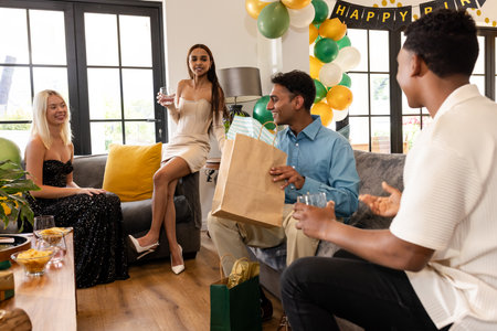 Friends celebrating birthday at home, exchanging gifts and enjoying conversation. Celebration, friendship, party, indoors, happiness, holidayの写真素材