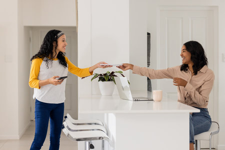 Mother and daughter sharing documents at home, smiling and using smartphone. Family, communication, bonding, technology, happiness, lifestyleの写真素材