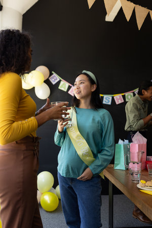 Pregnant woman at baby shower talking with friend, enjoying celebration. Pregnancy, motherhood, friendship, togetherness, happiness