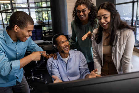 Diverse business team collaborating and laughing together at office desk. Teamwork, collaboration, diversity, meeting, professional, brainstorming