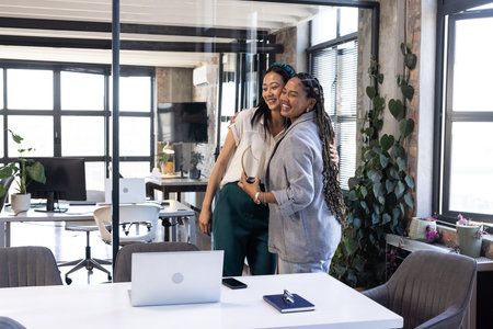Colleagues hugging in modern office, celebrating success with joyful expressions. Teamwork, collaboration, celebration, corporate, friendship, happinessの写真素材