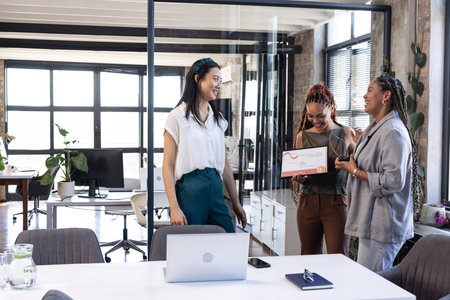 In office, diverse businesswomen sharing award and celebrating success together. teamwork,...