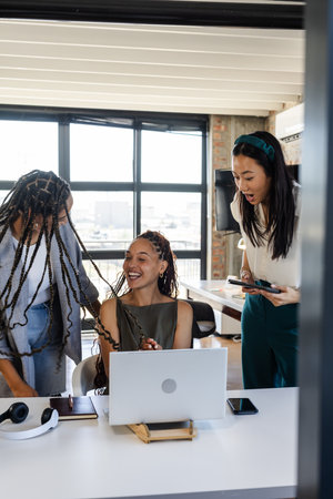 Celebrating success, colleagues sharing joyful moments around laptop in modern office. Teamwork, collaboration, business, achievement, celebration, corporateの写真素材