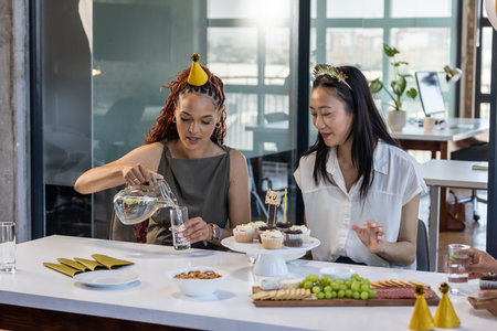 At office, diverse women celebrating with snacks and drinks during business party. Celebration, corporate, diversity, networking, event, office lifeの写真素材