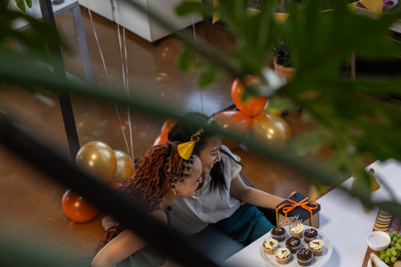 Celebrating at office, two women smiling at cupcakes during birthday party. Celebration, colleagues, office culture, sweets, friendship, coworkersの写真素材