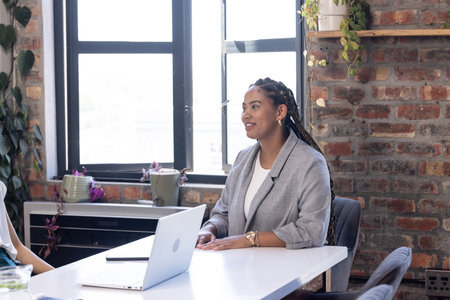 Smiling businesswoman in office discussing project with colleague at desk. teamwork, collaboration, professional, corporate, meeting, discussionの写真素材