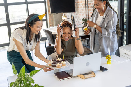 Colleagues celebrating birthday in office with cupcakes and joyful laughter. Coworkers, teamwork, celebration, office culture, workplace, happinessの写真素材