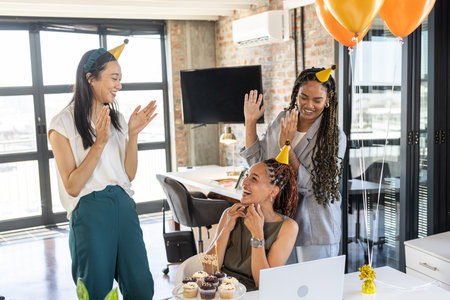 In office, diverse colleagues clapping and smiling with cupcakes and balloons. Celebration, teamwork, corporate, event, diversity, inclusiveの写真素材