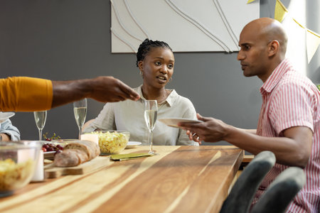 Friends sharing dinner and conversation at home, enjoying cozy evening together. Friendship, gathering, dining, warmth, meal, relationshipsの写真素材