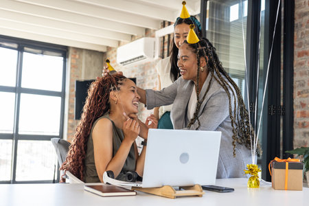 Colleagues celebrating success at office, wearing party hats and laughing joyfully. Teamwork, achievement, celebration, coworkers, happiness, corporateの写真素材