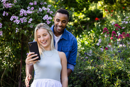 Couple enjoying outdoor garden, taking selfie with smartphone, smiling together. friendship, lifestyleの写真素材