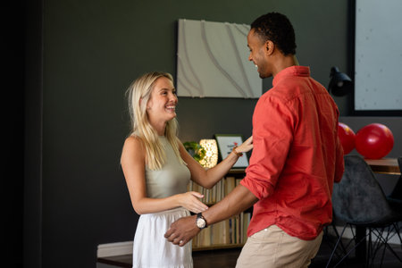 Couple dancing and smiling at home during joyful celebration with balloons. party, happiness, festive, romance, togetherness, lifestyleの写真素材