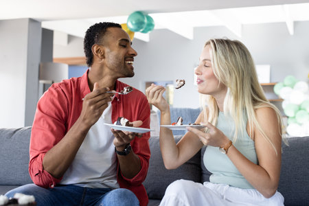 Couple enjoying cake together on sofa, celebrating joyful moments at home. celebration, happiness, dessert, lifestyle, bonding, leisureの写真素材