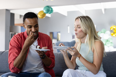Enjoying cake together, African American man and woman celebrating at home. Celebration,...