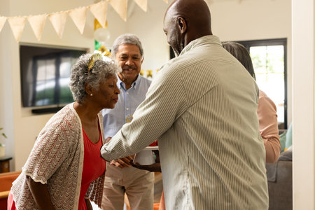 Exchanging gifts, elderly couple smiling at family gathering during celebration. joyful, festive,...