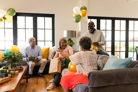 Celebrating birthday at home, African American family exchanging gifts and laughing together. celebration, happiness, togetherness, joyful, multicultural, bondsの写真素材