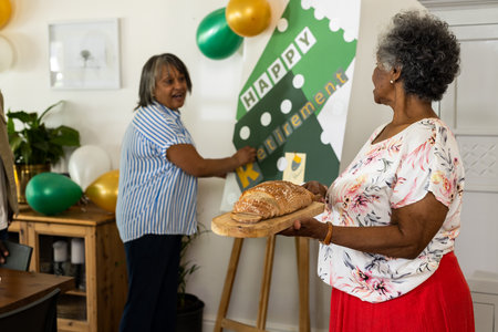 Women celebrating retirement at home with balloons and fresh bread. celebration, happiness, milestone, lifestyle, joy, leisureの写真素材