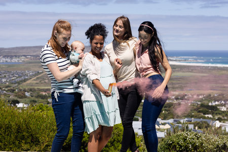 Friends celebrating outdoors with colorful powder, enjoying joyful moments together. Celebration, festival, friendship, diversity, happinessの写真素材