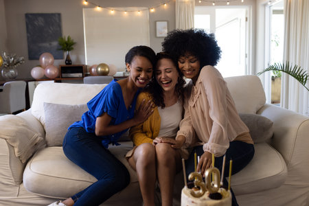 Friends celebrating 30th birthday at home, laughing and enjoying cake together. Celebration, friendship, party, milestone, birthday cake, happinessの写真素材