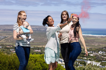 Women celebrating outdoors with smoke flare, smiling and enjoying scenic view. Celebration,...