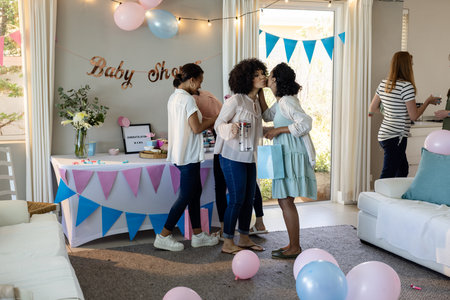 Friends celebrating baby shower, exchanging hugs and smiles in decorated living room. Celebration, friendship, happiness, family, decoration, joyfulの写真素材