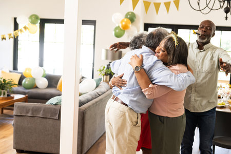 Family celebrating at home, hugging and enjoying festive decorations and balloons. Celebration, togetherness, holiday, happiness, partyの写真素材
