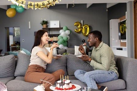 Friends enjoying cake and celebrating birthday at home with festive decorations. Celebration, party, friendship, happiness, gathering, festivityの写真素材