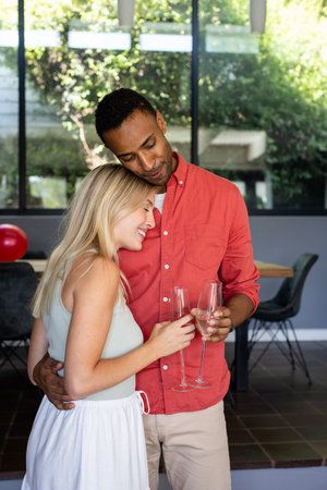 Couple celebrating at home, holding champagne glasses and sharing joyful moment. Celebration, happiness, romance, toast, anniversary, togethernessの写真素材