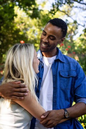 Couple embracing outdoors, smiling and enjoying sunny day in park. Love, relationship, happiness, romance, bonding, leisureの写真素材