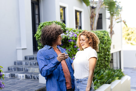 Young diverse couple laughing and enjoying conversation outdoors in garden setting. happiness,...