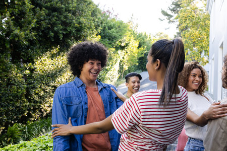 Laughing together, friends having fun at outdoor gathering in sunny garden. Friendship, celebration, summer, happiness, leisureの写真素材
