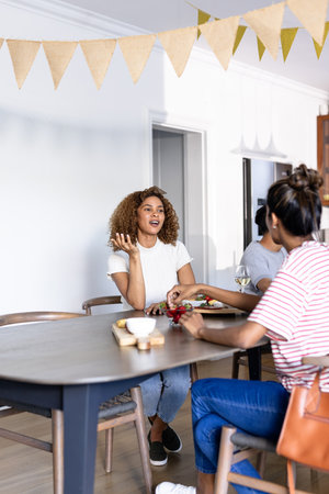 Young women enjoying conversation and drinks at home, sharing laughter and stories. Friendship, bonding, leisure, chatting, celebration, relaxationの写真素材