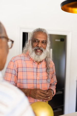 Senior man with long hair talking and smiling with friend in kitchen. Conversation, friendship, happiness, lifestyle, leisure, domesticの写真素材