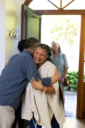 Senior people sharing joyful hugs and laughter, greeting warmly at home. Friendship, togetherness, happiness, celebration, affection, warmthの写真素材